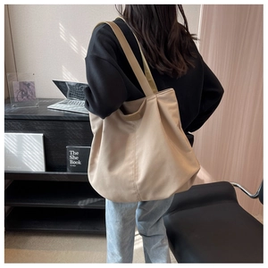Rear view of model carrying a spacious khaki canvas tote bag for business commuting