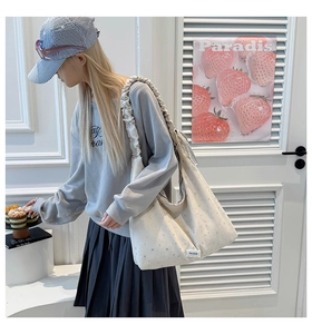 Detail of star pattern canvas tote bag with ruffled shoulder strap and woven label