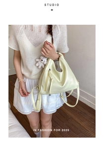 Detail of cream yellow hobo bag with zipper pocket and cute white plush bear charm