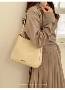 Close-up of vintage beige tote bag with pleated leather texture and gold logo detail