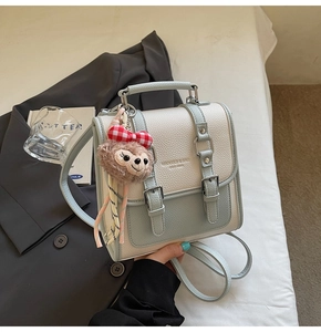 Detail of light blue and cream small square bag with cute brown bear charm