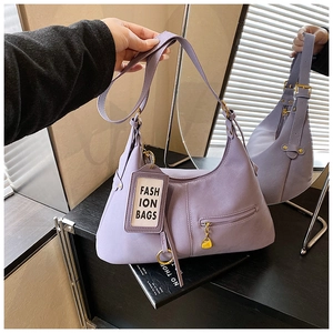 Détail de sac bandoulière demi-lune violet avec étiquette mode et fermeture éclair latérale