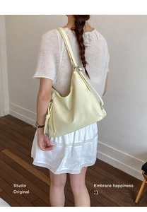 Detailed close-up of cream PU leather tote bag featuring side zipper and long pullers
