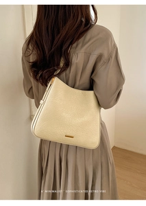 Détail du sac cabas en cuir texturé beige avec un élégant accent en métal doré