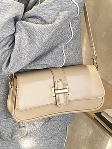 Minimalist beige rectangular flap crossbody bag with gold buckle shown on a model