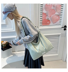 Detail of mint green tote bag featuring ruffled shoulder straps and white dot pattern