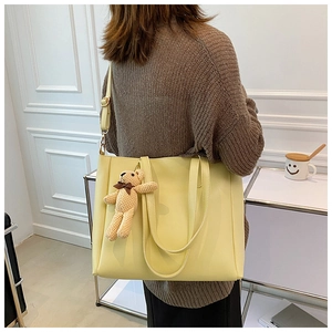 Stylish large capacity light yellow leather tote bag with a brown bear charm for women