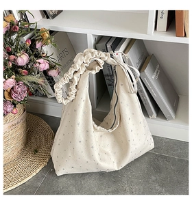 Detail of cream canvas tote bag with silver star print and ruched shoulder strap design