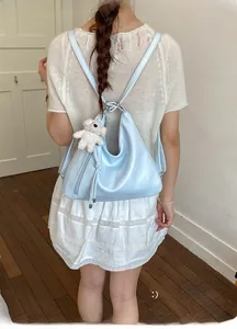 Detail view of light blue versatile hobo bag with cute white teddy bear plush charm