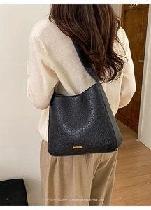 Detail of black vintage cracked texture hobo bag with wide shoulder strap on a model