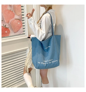 Detail der blauen gepunkteten Denim-Einkaufstasche mit Textdruck am Model getragen