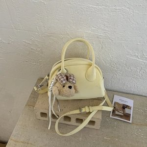 Detail of light yellow bowling bag with soft faux leather texture and cute bear charm
