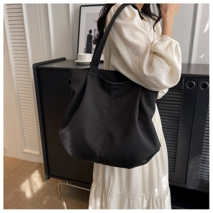 Detail of minimalist black nylon tote bag showing embossed leather trim and fabric texture