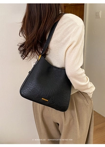 Détail d'un sac cabas rétro noir avec boucle en métal doré et texture de cuir grainé