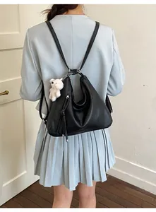 Rear view of black PU leather backpack with teddy bear charm on model in blue blazer