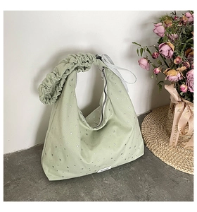 Detail of light green canvas tote bag featuring silver star print and ribbon handles