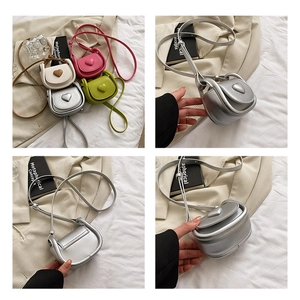 Detail view of mini heart-shaped crossbody bags in silver, cream, pink and green leather