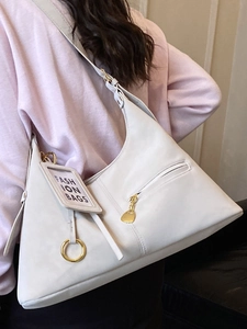 Sac hobo minimaliste beige avec fermetures dorées et étiquette décorative pour femme