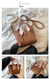 Dettaglio borsa a secchiello in pelle marrone con foulard e accessori metallici oro