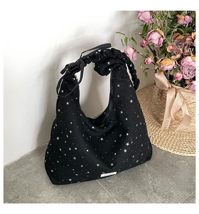 Close-up of black star pattern canvas tote bag with scrunchie handle and bow detail