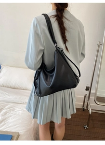 Detail view of a large black minimalist tote bag on model's shoulder for daily commute