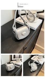 Detailed view of mini silver heart-shaped leather crossbody bag for girls on a wooden desk