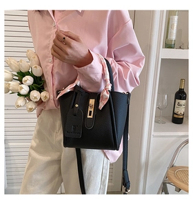 Borsa a secchiello in pelle nera con foulard rosa sul manico indossata dalla modella