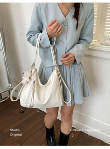 Detail of hobo bag featuring tassel zipper and a cute beige plush bear charm