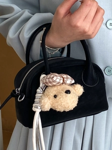 Fashionable black leather bowling bag for women featuring a cute plush puppy charm