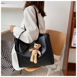 Detail of minimalist black tote bag with cute handmade knitted bear charm accessory