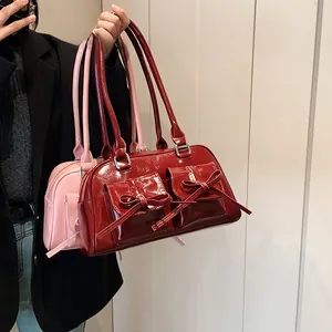 Detail of glossy patent leather handbag with bow accents in burgundy and pink