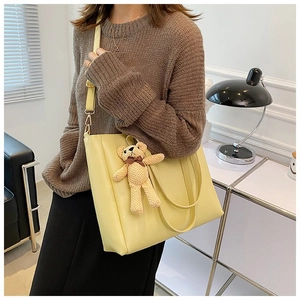 Detail of light yellow tote bag with detachable strap and cute bear keychain charm