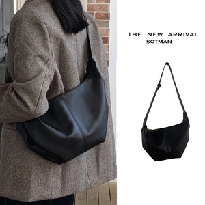 Detail of minimalist black leather hobo bag showing texture and adjustable strap