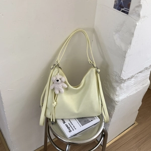 Detailed side view of cream yellow PU leather tote bag with a cute white plush bear pendant