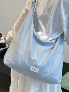 Blue canvas tote bag with star prints and ruffle strap shown on model shoulder