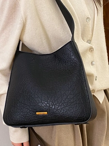 Retro black ostrich textured tote bag with gold logo plate shown on model