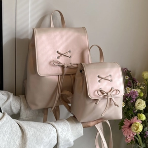 Size comparison of large and mini light pink leather backpacks with ribbon bow details