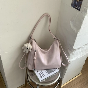 Detail of light pink PU leather bag with fringe zipper and white plush puppy charm