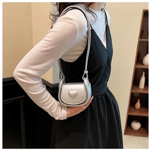 Silver mini heart crossbody bag for girls showing compact size on a model shoulder