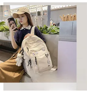 Close-up of off-white multi-pocket backpack with plush bear charm in a cafe setting