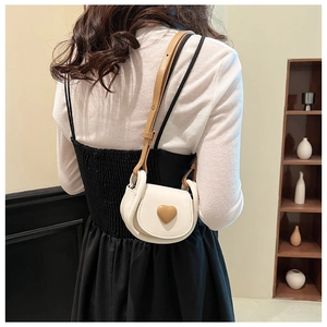 Detail showing mini crossbody bag with heart ornament on a model for size perspective