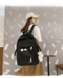 Detail view of black nylon backpack with multiple zipper pockets and cute cartoon pins