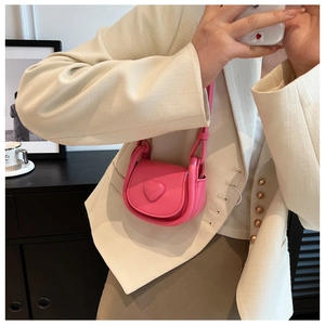 Mirror selfie showing the detail of a pink mini heart crossbody bag with embossed heart