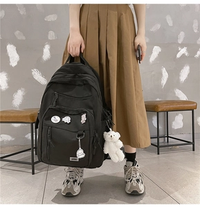 Close-up of black high-capacity student backpack featuring cute charms and functional pockets