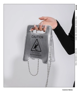 Gros plan du sac en métal argenté avec inscription noire caution et catwalk