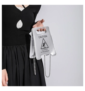 Vue détaillée du sac à main miroir argenté avec texte CAUTION et chaîne à billes