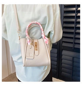 Dettaglio borsa a secchiello beige in pelle con foulard di seta a quadretti rosa