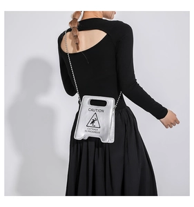 Détail du sac argenté en forme de panneau de signalisation avec bandoulière chaîne