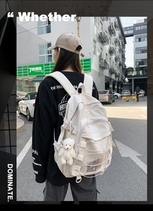 Detail of beige student backpack featuring mesh pockets and cute plush bear charm