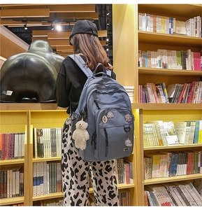 Blue large capacity student backpack with cute badges and bear charm in library setting